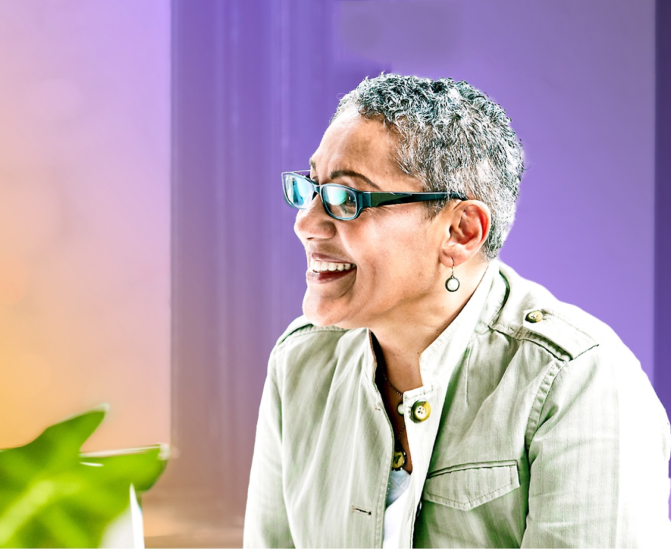 A woman wearing glasses is sitting at a desk with a laptop.