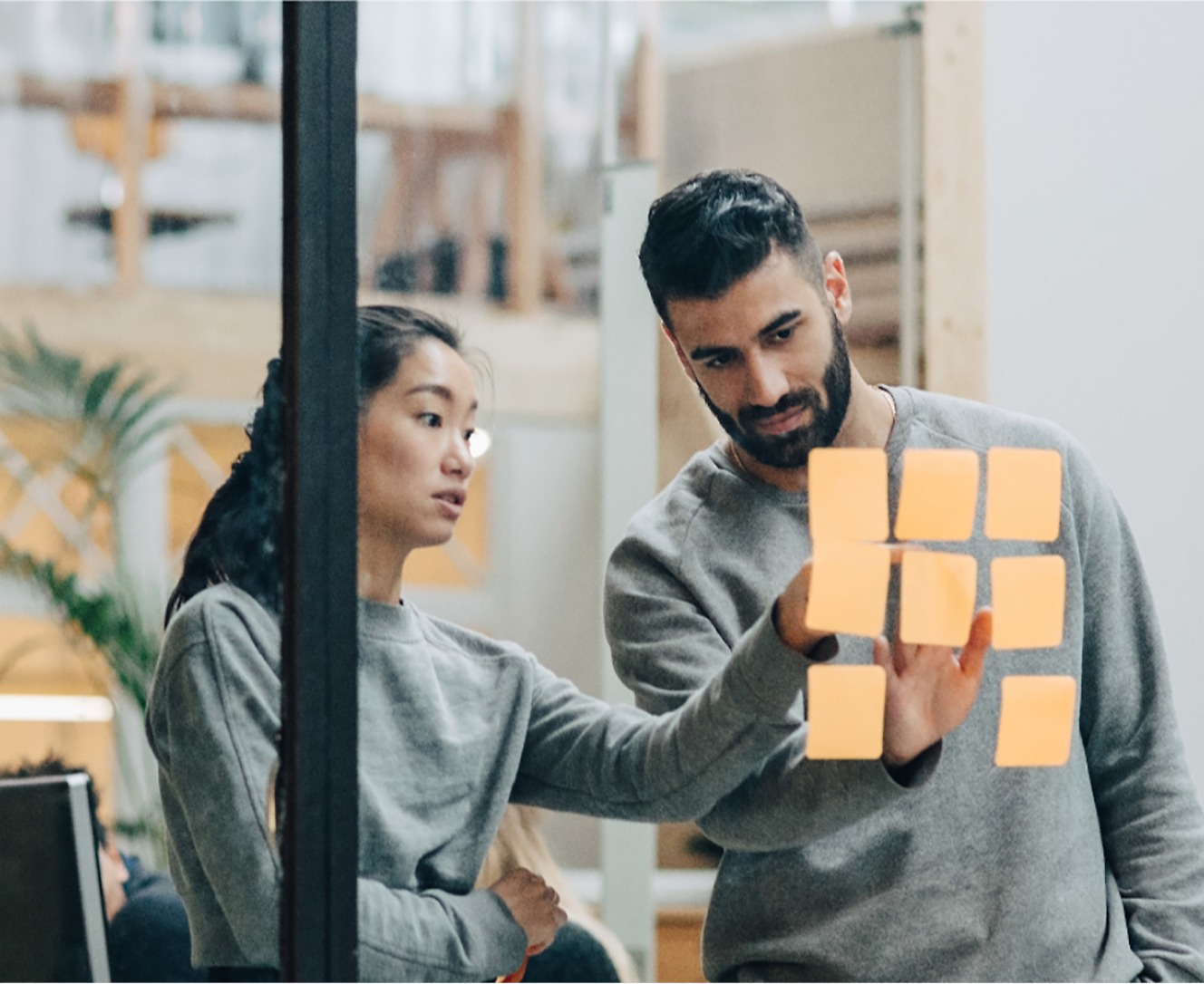 A man and woman looking at sticky notes in an office.