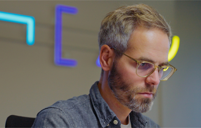 Ein Mann mit Brille, der an einem Schreibtisch sitzt