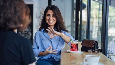 Two young woman speak in sign language.