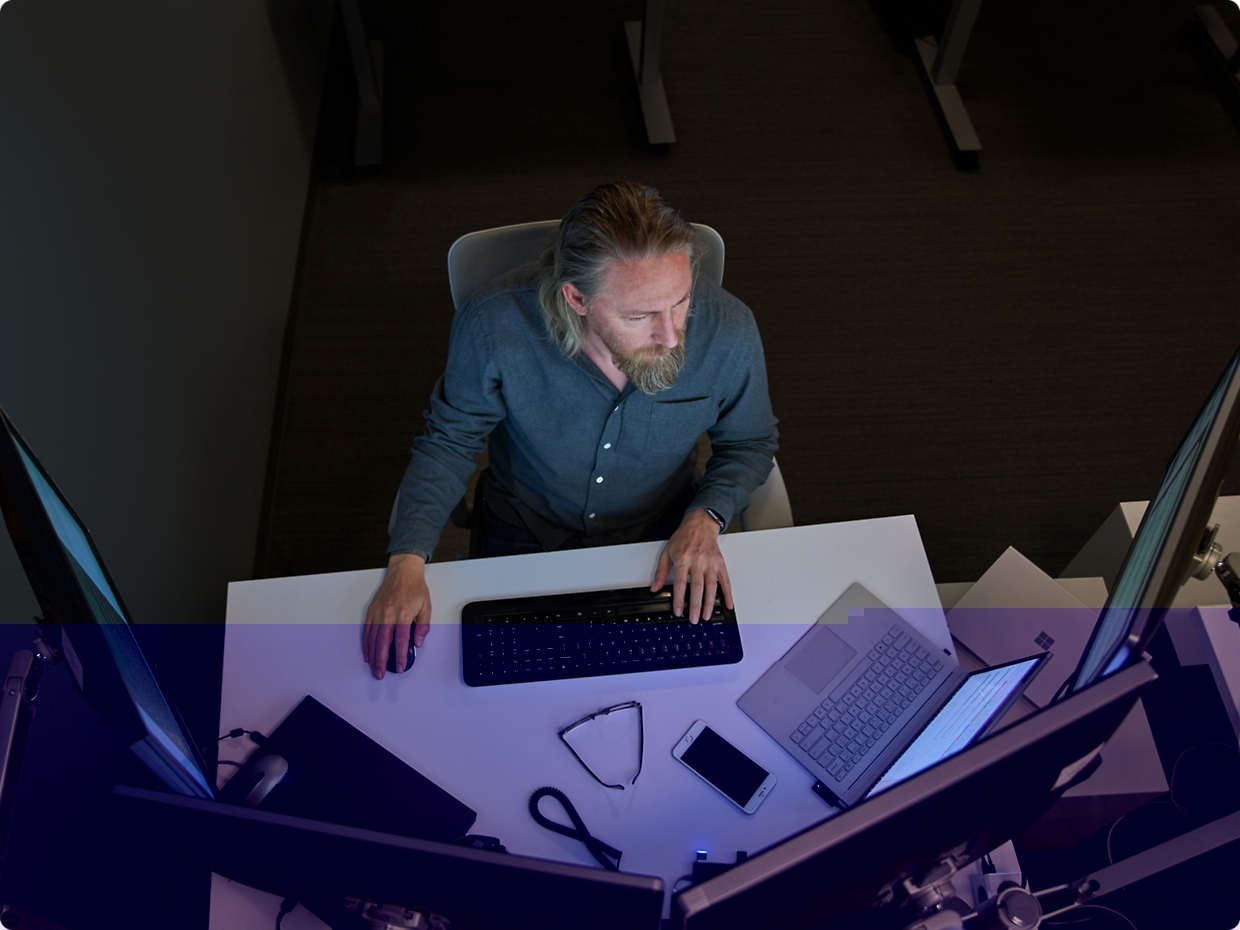 Two men focused on a computer screen in an office setting, one with his chin resting on his hand.