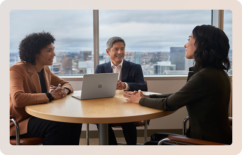 Three people seated at a round table in an office setting