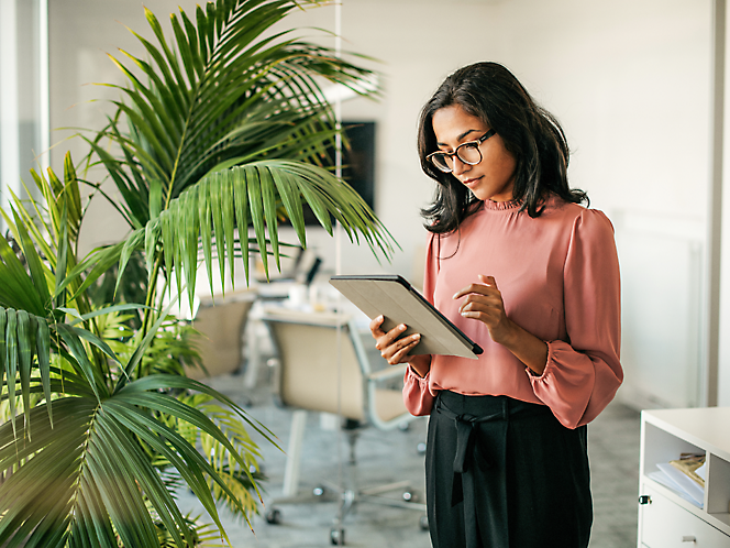 A person standing looking at a tablet.