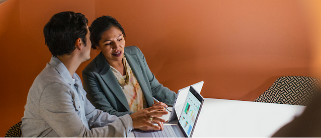 Two person's sitting at a table with a computer