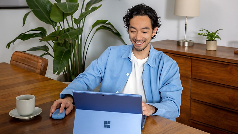 Een persoon die een Surface-apparaat gebruikt in de laptopmodus aan een eettafel