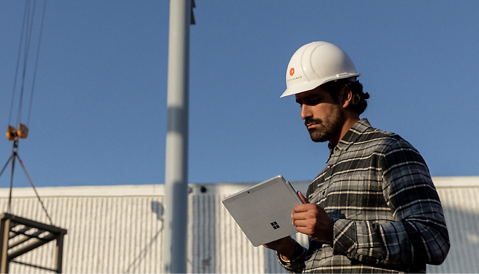 Seseorang mengenakan helm pengaman sedang menggunakan perangkat Surface