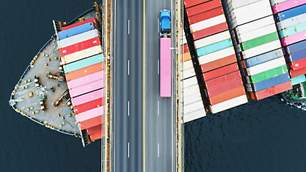 Das Schiff mit dem Container ist im Fluss, und ein Lastwagen steht auf der Brücke