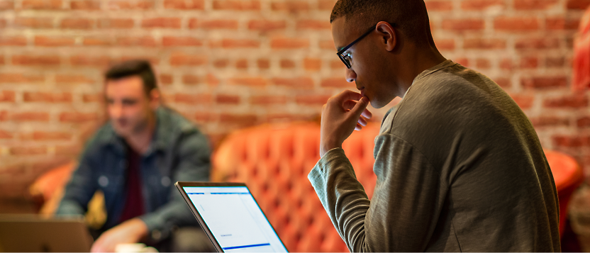 Two men focused on their work in a casual office setting, with one using a laptop in the foreground.