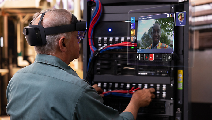 A technician wearing a vr headset is working on a complex array of cables in an industrial setting, with a digital interface visible