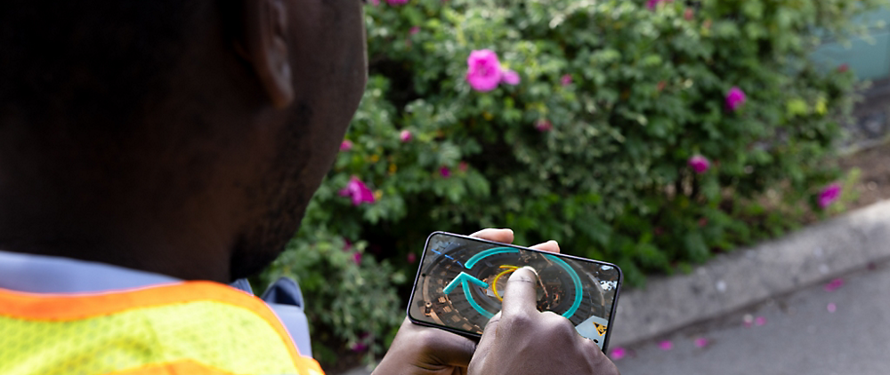 A man on a video call discussing wiring installation steps displayed next to an open hardware device with marked components.