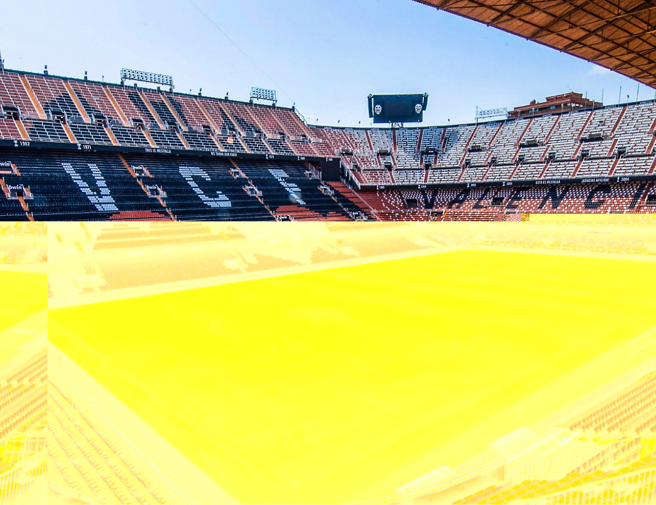 The inside of a soccer stadium with an orange field.