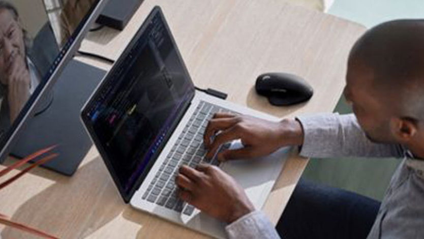 A man works on a Surface device at his desk