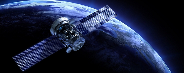 Een satelliet met uitgebreide zonnepanelen draait om de aarde, tegen de donkere achtergrond van de ruimte.