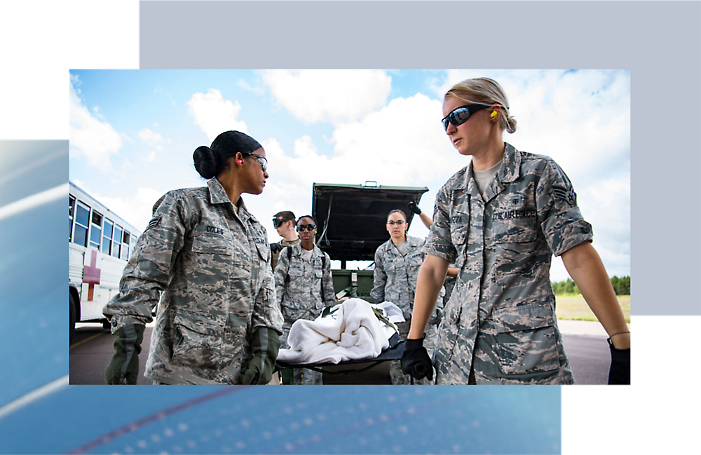 Four military personnel in camouflage uniforms conversing beside a vehicle, with a blue bus 