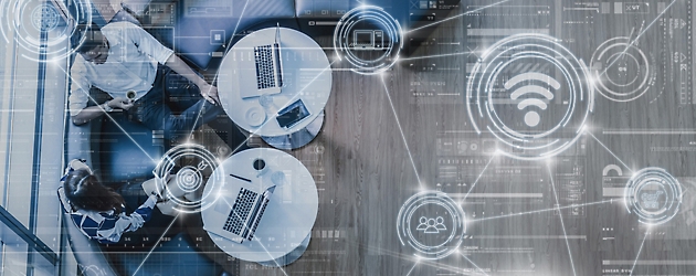 Vue d’ensemble d’un espace de travail d’entreprise avec des personnes utilisant des ordinateurs portables sur des bureaux superposés avec des icônes numériques de technologie et de connectivité réseau.