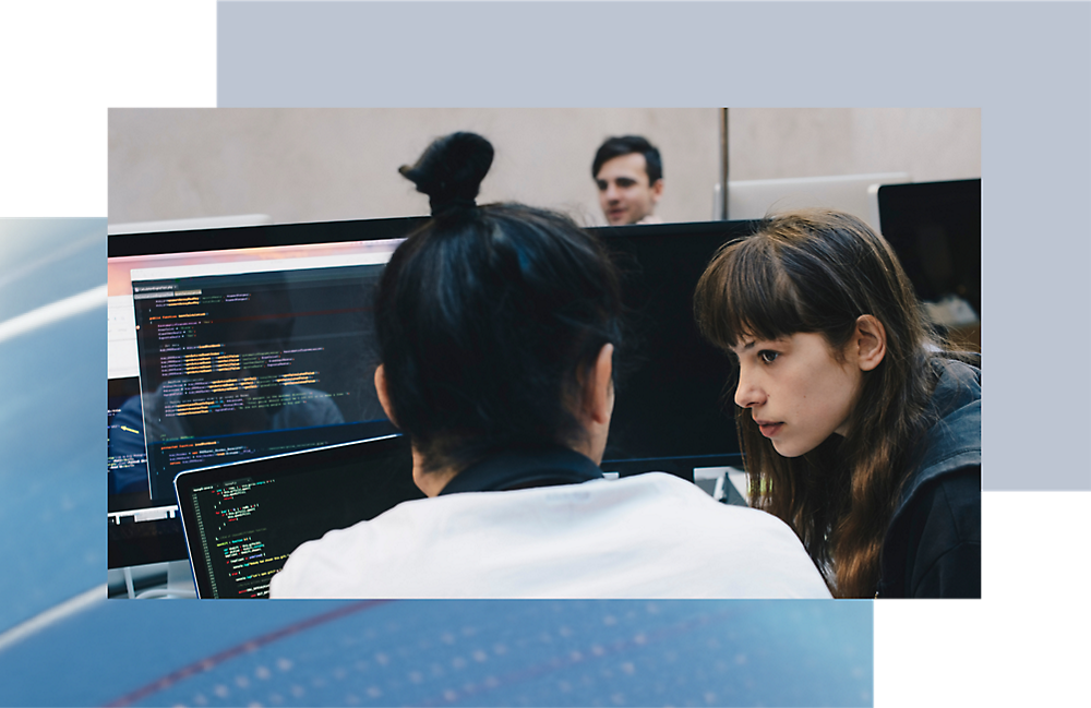 Two people analyzing code on a computer screen in a modern office setting.