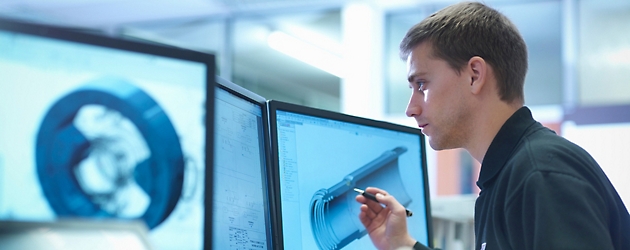 Man analyzing a 3d model on computer screens in a technical or engineering office environment.