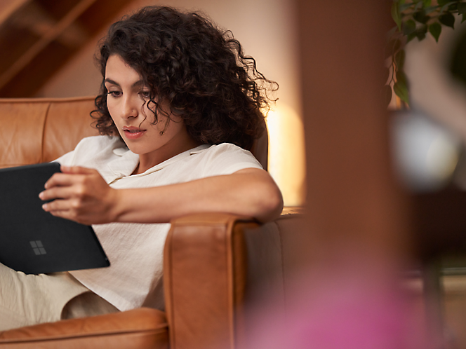 A person sitting on a chair looking at a tablet