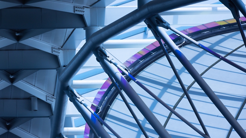 Abstract interior view of a modern building with blue tones, featuring crisscrossing metal beams and glass 