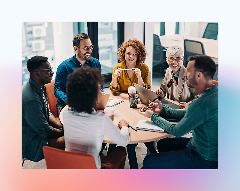 A group of people sitting around a table smilling and talking with each other