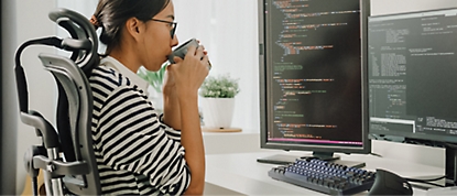 A person drinking from a cup and working on dekstop