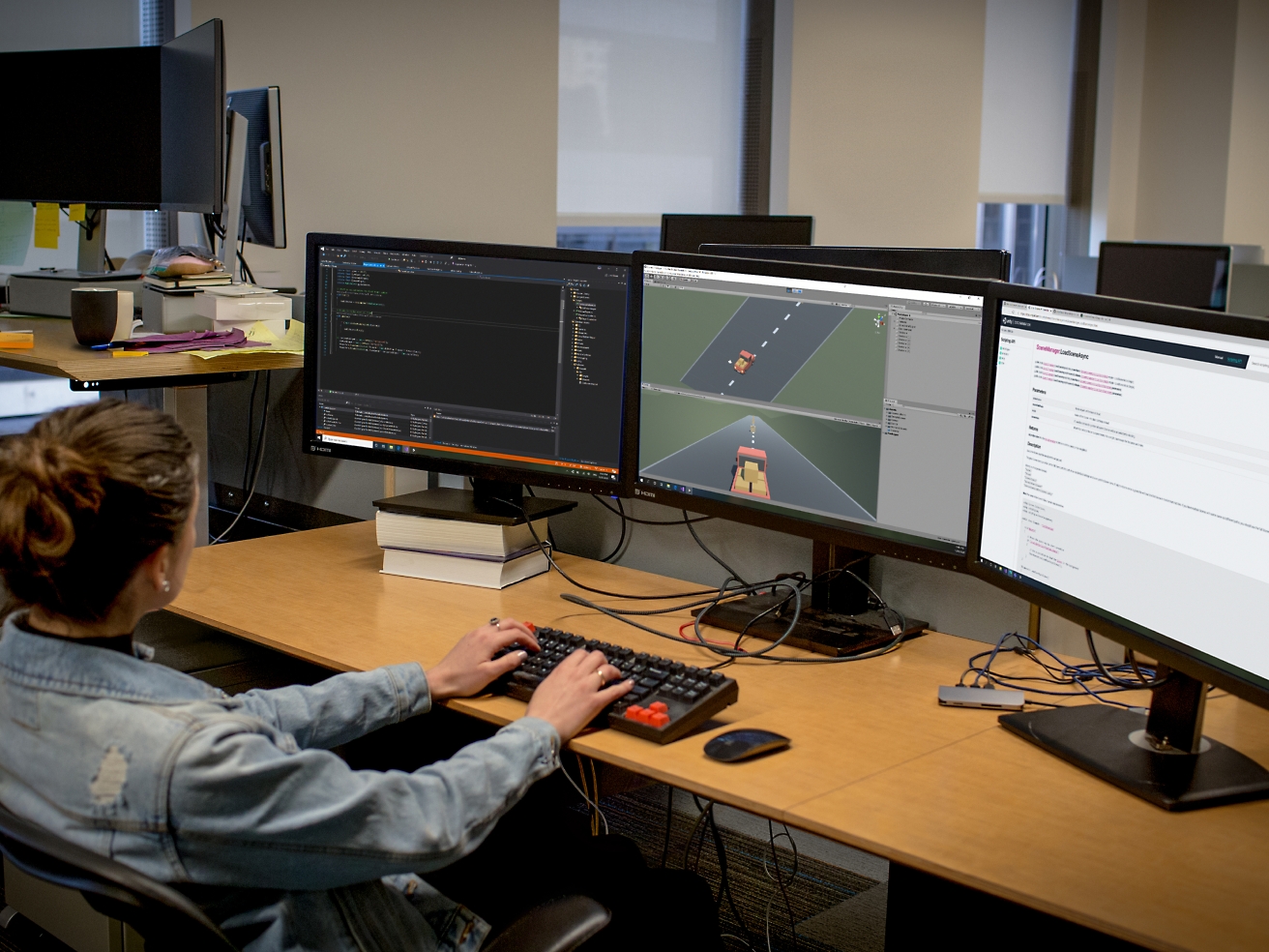 Una desarrolladora de software trabaja en una oficina con varios monitores, codificando y depurando software.