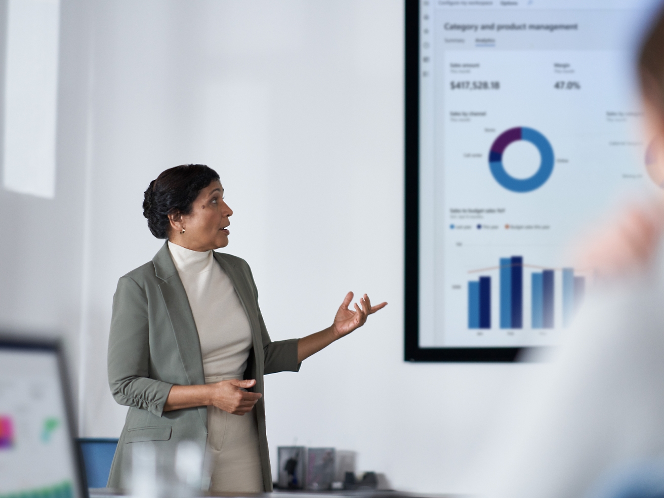 Una mujer profesional presenta datos financieros en una pantalla a su público en una moderna oficina.