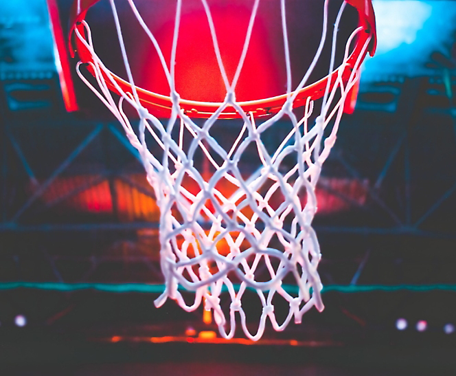 Basketball hoop illuminated by red light, viewed from below the net.