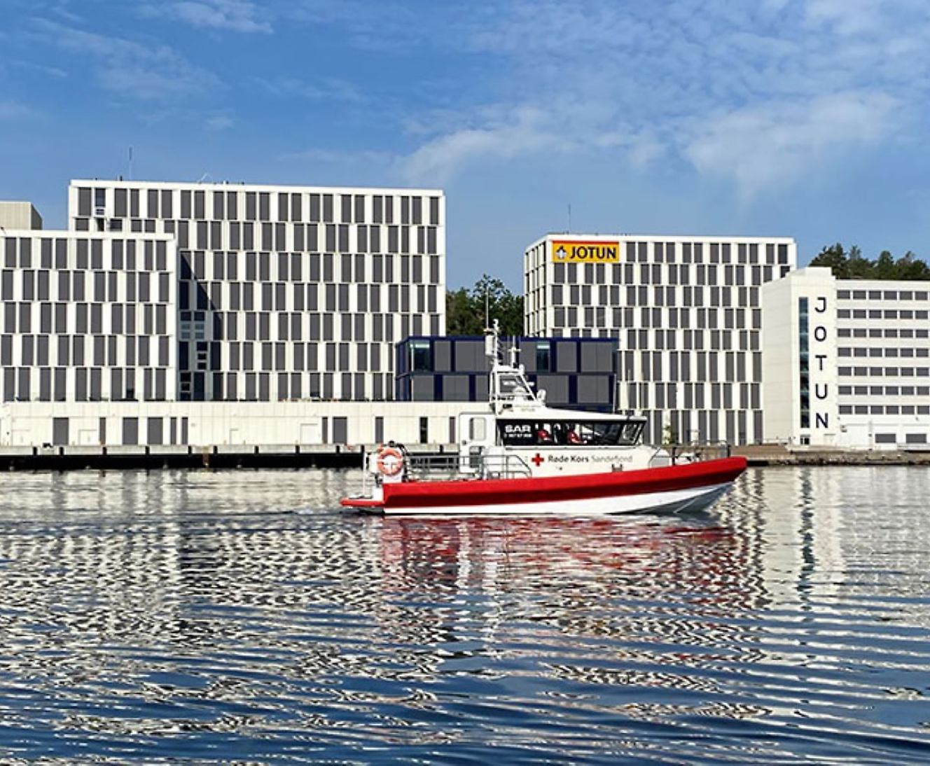 A boat on the water infron of a Jotun building