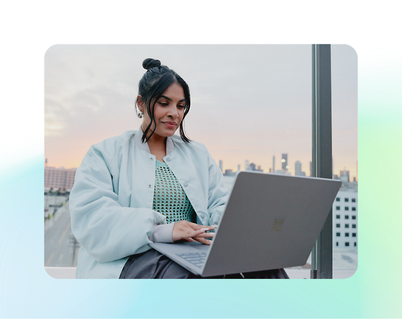 A person sitting on a window sill with a computer