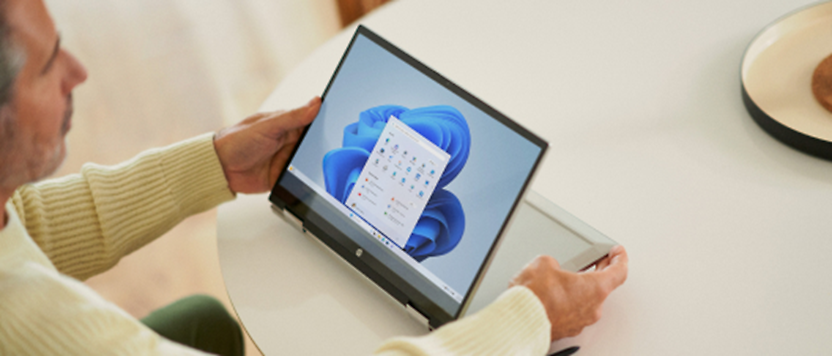 A man sitting at a table using a laptop computer