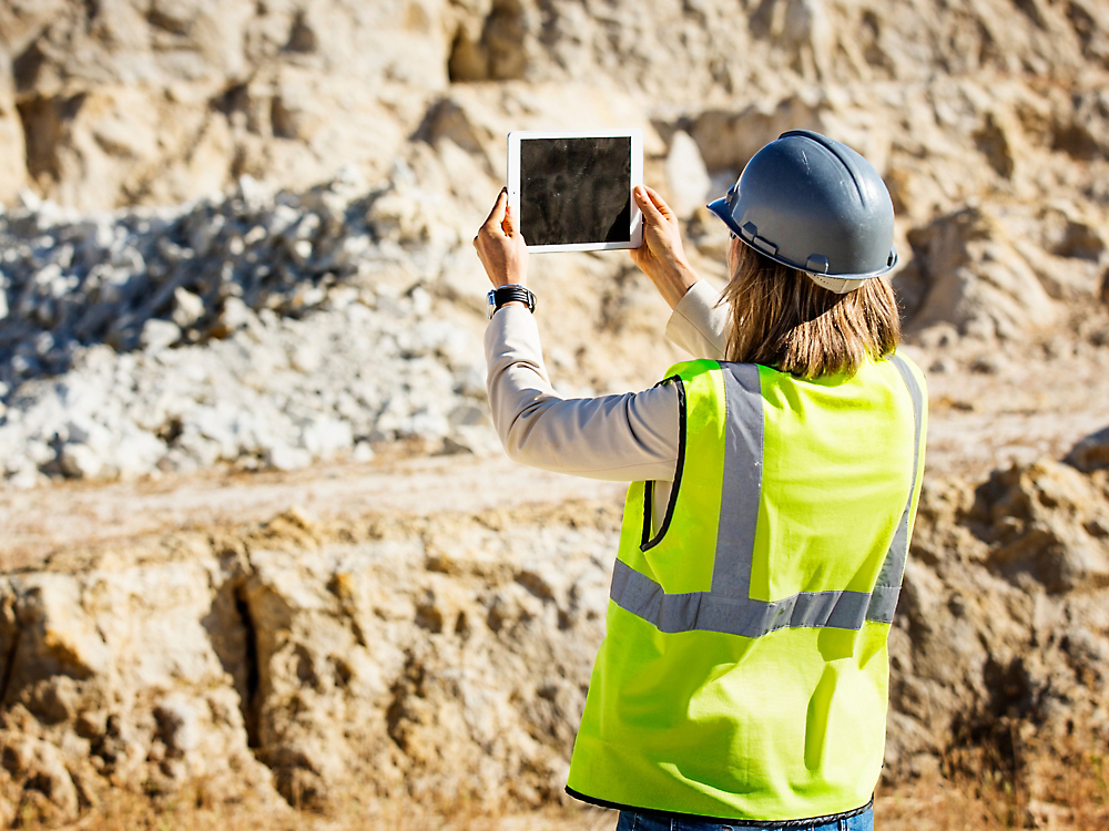 Een persoon in een veiligheidsvest en helm die een tablet vasthoudt