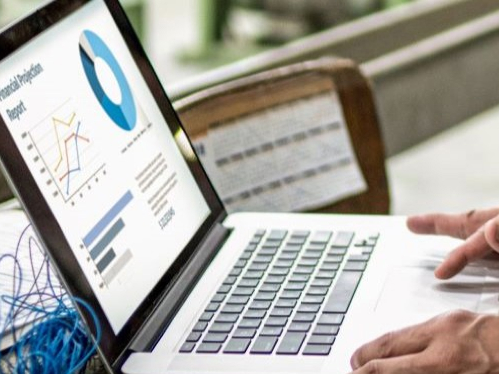 A person analyzing statistical data on a laptop screen next to printed reports.