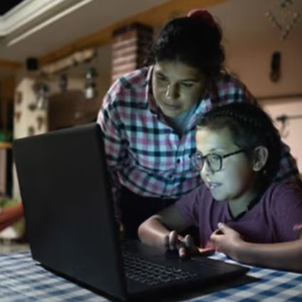 Mother and child working on a laptop in a rural home setting.