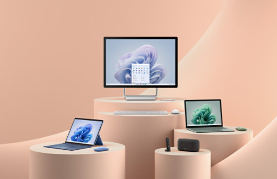 Un affichage de plusieurs appareils Surface et accessoires technologiques sur un fond rose pêche.
