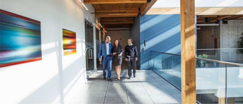 A group of people walking down a hallway in an office building.