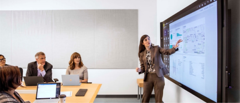 A group of people sitting at a table in front of a large screen.