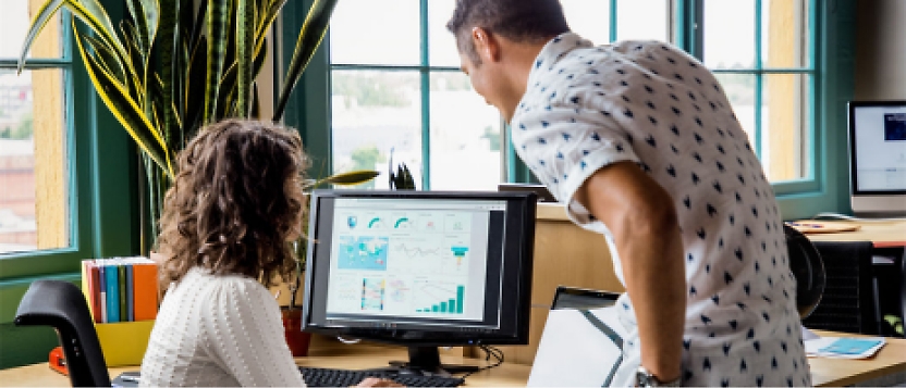 Two people working on a computer in an office.