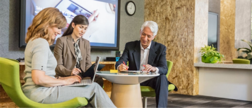 A group of people sitting around a table in an office.