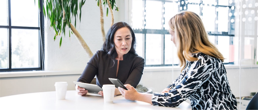 Two women sitting at a table talking to each other.