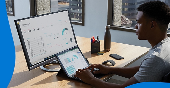 A person analyzing data being shown on a monitor at their desk.