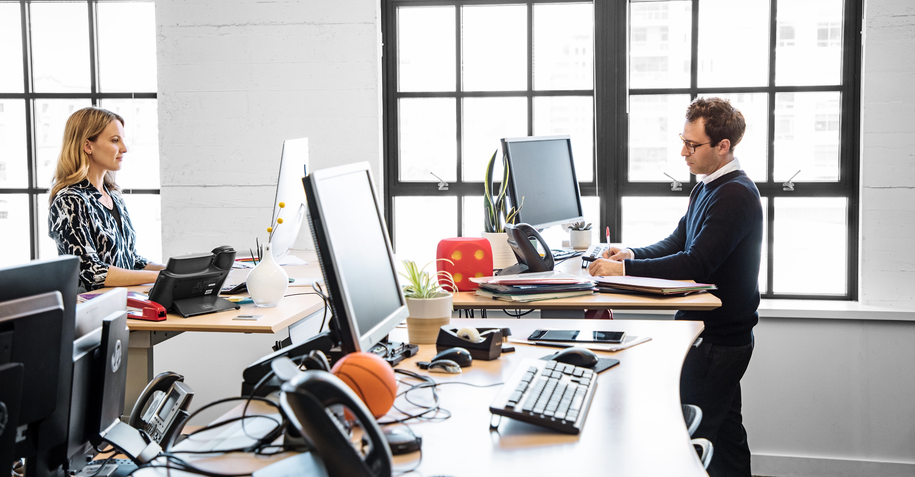 Two people working at standing desks in a contemporary office.