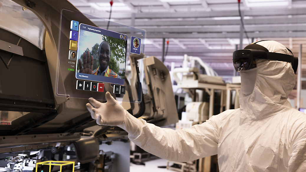 A technician in a protective suit analyzing data on a digital screen in a high-tech manufacturing facility.