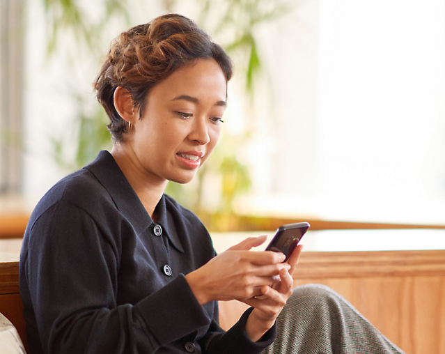 En person som sitter på en benk og ser på telefonen sin