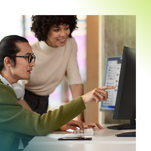 Two persons discussing over desktop in an office