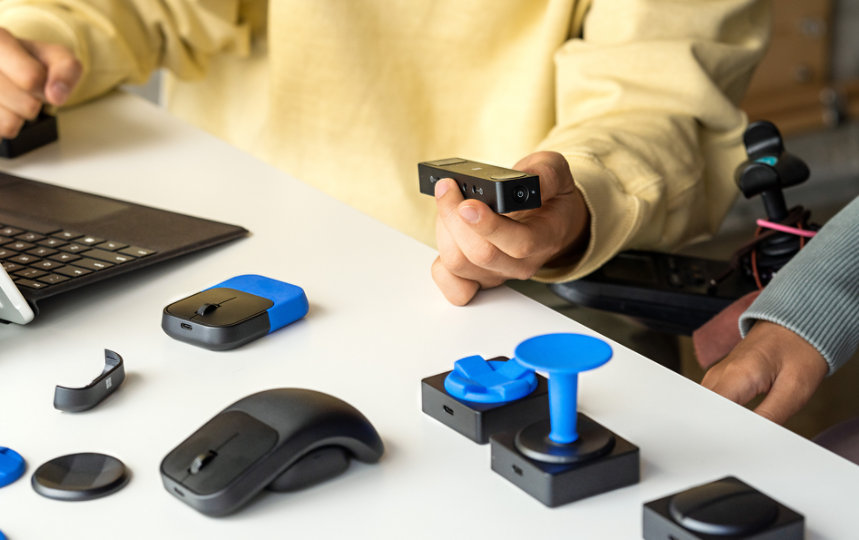 A person shows another person a variety of Microsoft Adaptive Accessories.