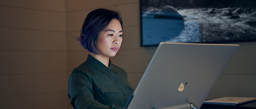 A person works on a large computer monitor in a room with a mounted photograph in the background.