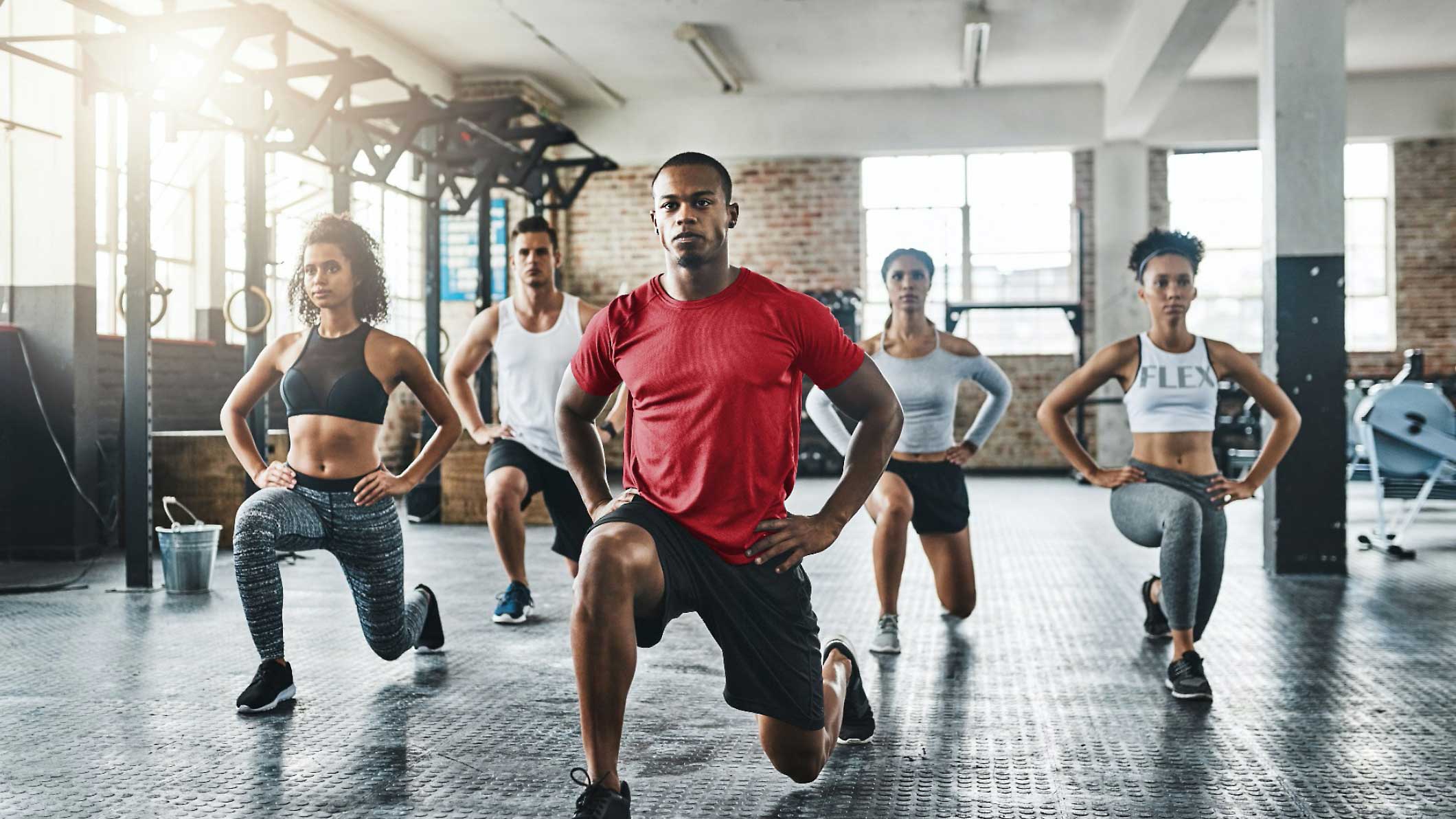 Eine Gruppe von Personen, die in einem Fitnessstudio einen Ausfallschritt machen.