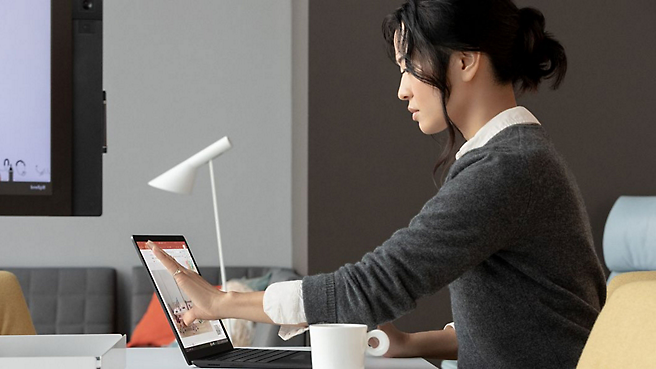 A woman is using a microsoft surface laptop.