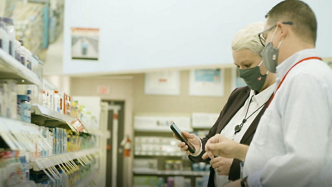 Dos personas con mascarillas en una farmacia.